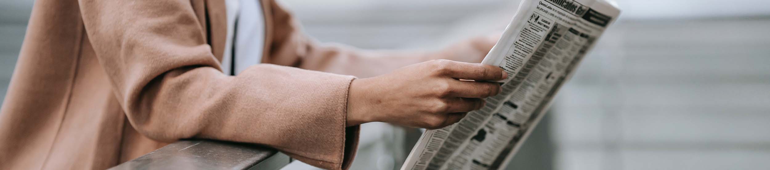 Eine junge Frau liest eine Zeitung.